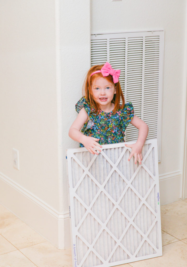 How to Improve Air Quality in Home by popular Houston lifestyle blog, Cake and Confetti: image of a little girl holding a Homestock USA air filter. 