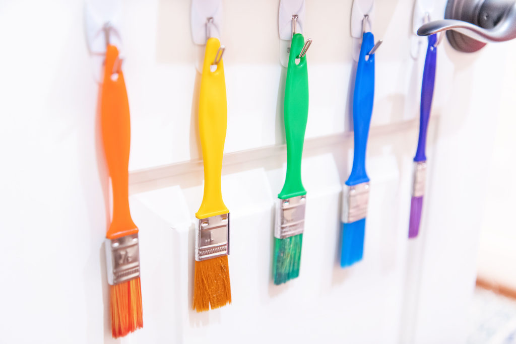 Craft Closet by popular Houston lifestyle blog, Cake and Confetti: image of paint brushes hanging on Command hooks that are mounted to a door. 